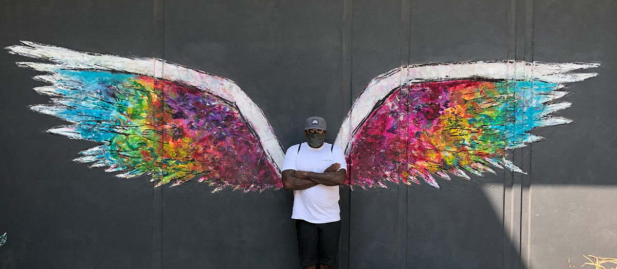 Singer Arnold McCuller standing against a wall with angel wing mural